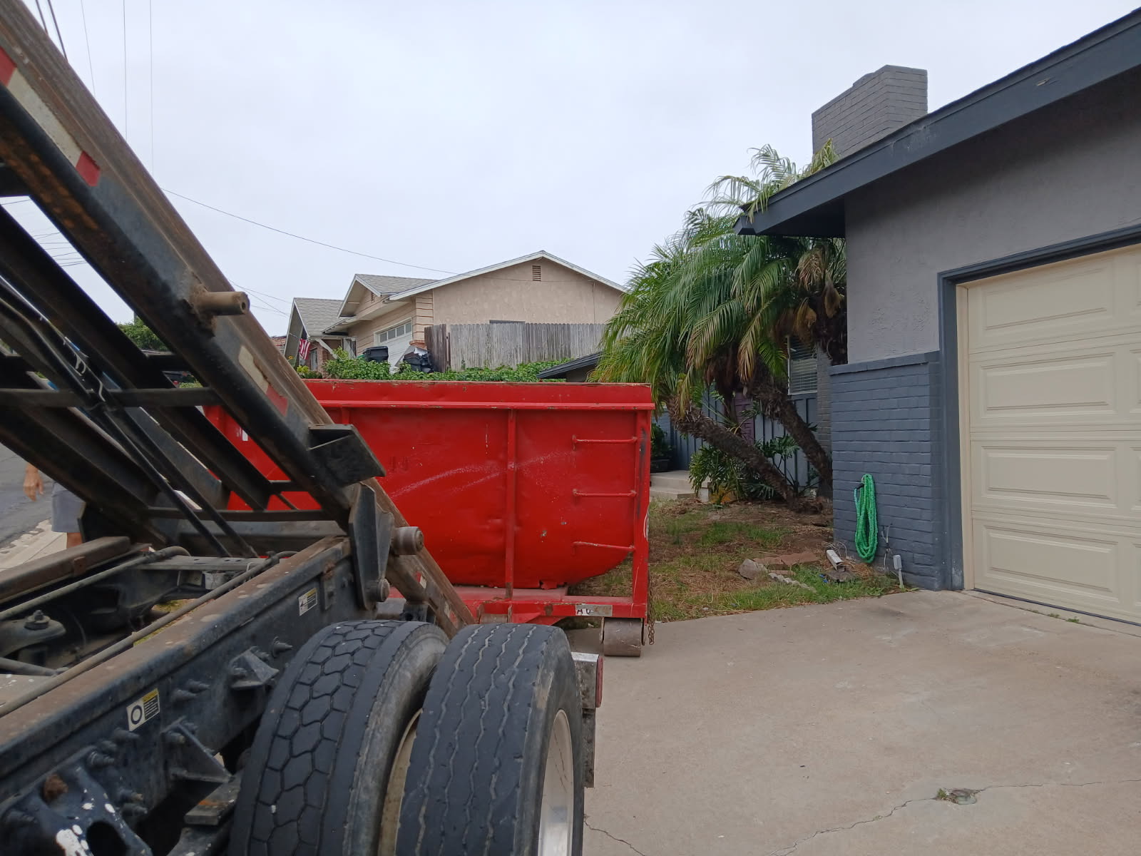 Red roll-off dumpster being placed in a Linda Vista front yard for a residential cleanout