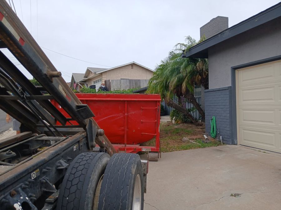 Red roll-off dumpster being placed in a Linda Vista front yard for a residential cleanout
