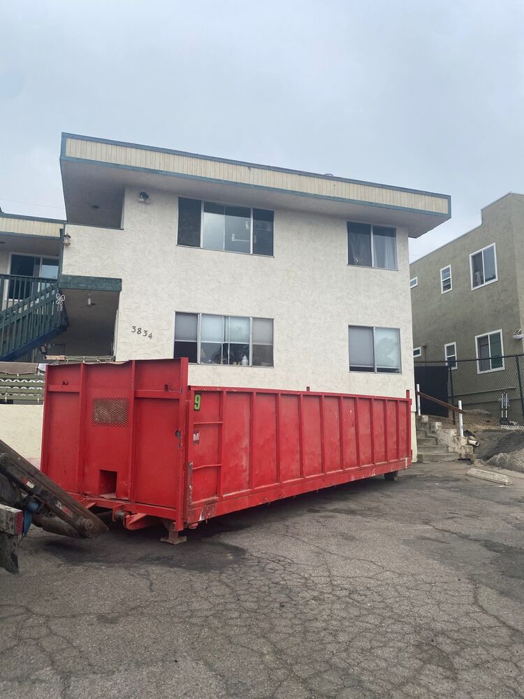 20-yard red roll-off dumpster delivered to a North Park apartment complex driveway for a multi-unit cleanout