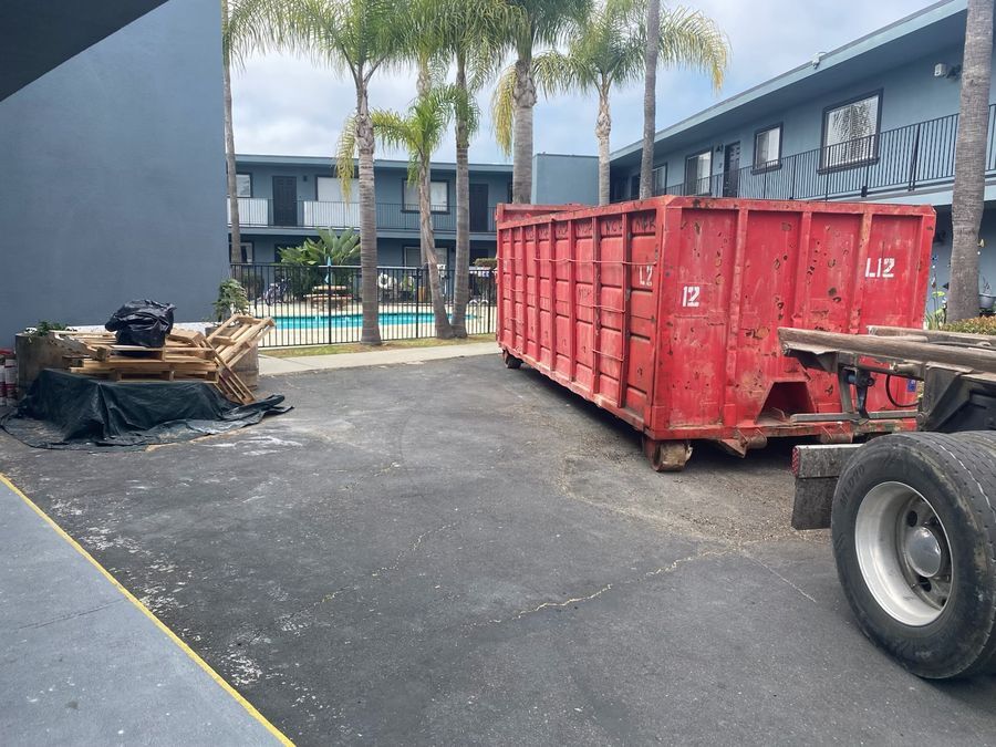 Red 40-yard Heverly & Sons roll-off dumpster delivered to an Oceanside apartment complex for a remodel